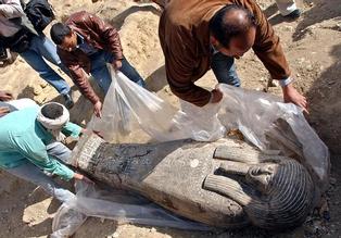 Egyptian workers cover an ancient wooden coffin shaped like a human body that dates back to the 26th Pharaoh Dynasty that ruled from 672 BC to 525 BC, in Sakkara, south of Cairo Wednesday, March 2, 2005. Australian archaeologists have discovered one of the best preserved ancient Egyptian mummies dating from about 2,600 years ago, Zahi Hawass, the head of Egypt's Supreme Council for Antiquities said. (AP Photo/Amr Nabil)