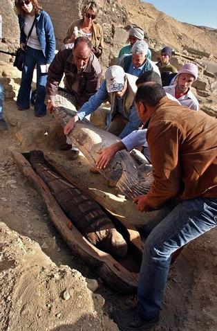 Egyptian workers open an ancient wooden coffin, shaped like a human body that dates back to the 26th Pharaoh Dynasty that ruled from 672 BC to 525 BC, in Sakkara, south of Cairo Wednesday, March 2, 2005. Australian archaeologists have discovered one of the best preserved ancient Egyptian mummies dating from about 2,600 years ago, Zahi Hawass, the head of Egypt's Supreme Council for Antiquities said. (AP Photo/Amr Nabil)